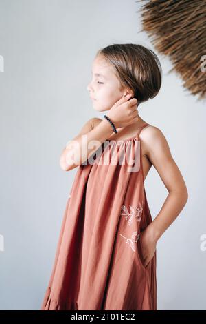Porträt eines Mädchens mit kurzer Frisur in einem Sommerkleid, die eine Hand glättet ihr Haar, die andere in ihrer Tasche Stockfoto
