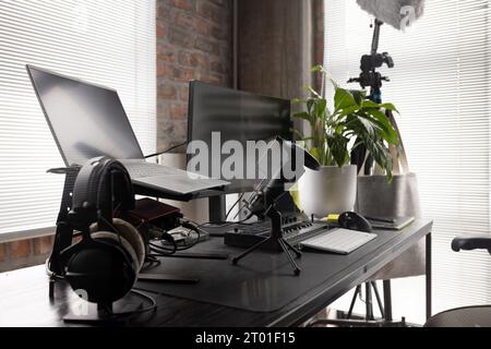 Podcasting-Einrichtung mit Kopfhörern, Computern, Tastatur und Mikrofon auf dem Schreibtisch zu Hause, Kopierraum Stockfoto