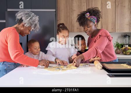 Afrikanische Familie schneidet Keksformen in einem Keksteig in der Küche. Horizontale erweiterte Familie. Stockfoto