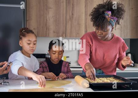 Afrikanische Familie schneidet Keksformen in einem Keksteig in der Küche. Horizontale erweiterte Familie. Stockfoto