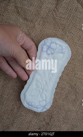 Damen hygienische tägliche Pads auf braunem Hintergrund. Frau Hand hält tägliche Pads. Hygienekonzept Stockfoto