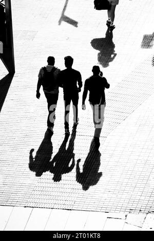 Silhouette von drei Männern, die zusammen auf der Straße laufen. Stockfoto