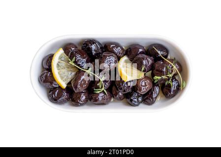 Schwarze Oliven auf einer weißen Porzellanplatte auf weißem Hintergrund Stockfoto