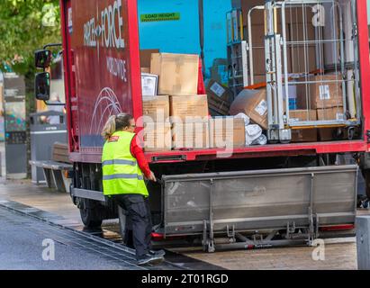 Postangestellte schließt Ladebordwand im voll beladenen Paketwagen im Stadtzentrum von Preston, Lancashire, Großbritannien Stockfoto