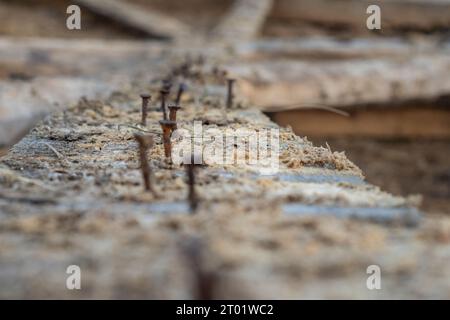 Alte, beschädigte Holzbalken liegen mit rostigen Nägeln, die nach dem Abriss der Scheune eingeklemmt wurden. Scheune. Stockfoto