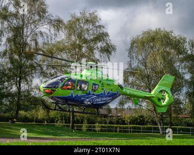 Der Great Western Air Ambulance hebt vor dem Gloucester Royal Hospital ab. Der hellhellhellgrüne und blaue Hubschrauber, Rufzeichen Helimed 65, ist Stockfoto