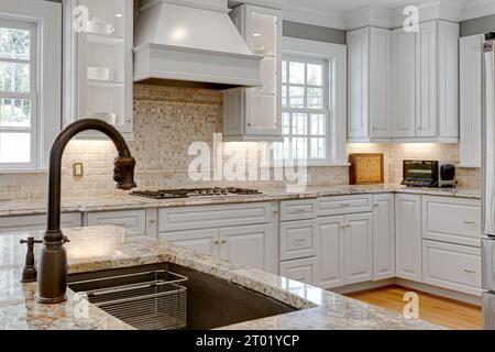 Großes Waschbecken mit Wasserhahn und luxuriöse Kücheneinrichtung mit Backsplash aus Stein im Hintergrund Stockfoto