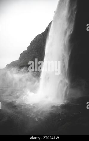 Seljalandsfoss Wasserfall Seitenansicht schwarz-weiß bei regnerischem Wetter, Island, vertikale Aufnahme Stockfoto