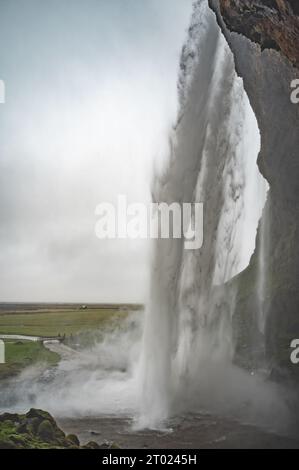 Unter dem Seljalandsfoss Wasserfall, Seitenansicht, Island, vertikale Aufnahme Stockfoto