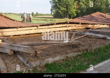 Die Überreste eines alten, zerstörten Metalldachs liegen nach dem Abriss der Scheune auf dem Boden. Tag Stockfoto