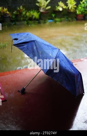 Blauer Regenschirm auf einem Sitout eines Hauses in kerala, Rain, Thulsi thara, Chavitti Stockfoto