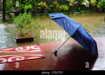 Blauer Regenschirm auf einem Sitout eines Hauses in kerala, Rain, Thulsi thara, Chavitti Stockfoto