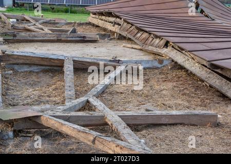 Die Überreste eines alten, zerstörten Metalldachs liegen nach dem Abriss der Scheune auf dem Boden. Tag Stockfoto