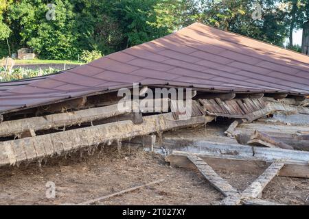 Die Überreste eines alten, zerstörten Metalldachs liegen nach dem Abriss der Scheune auf dem Boden. Tag Stockfoto