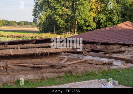 Die Überreste eines alten, zerstörten Metalldachs liegen nach dem Abriss der Scheune auf dem Boden. Tag Stockfoto