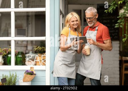 Glückliche Ältere Ehepaare, Die Kleinunternehmer Mit Einem Digitalen Tablet Und Kaffee Trinken Stockfoto