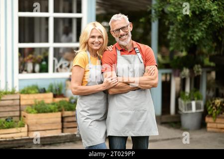 Porträt Eines Glücklichen Reichen-Bauernpaares, Das Draußen In Der Nähe Ihres Gewächshauses Steht Stockfoto