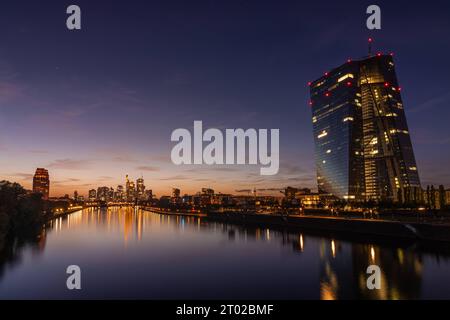 Die Europäische Zentralbank EZB und die Frankfurter Skyline die Lichter der Europäischen Zentralbank EZB und der Frankfurter Bankenskyline spiegeln sich am Abend nach Sonnenuntergang im Main. Frankfurt am Main Osthafen Hessen Deutschland *** die Europäische Zentralbank EZB und die Frankfurter Skyline die Lichter der Europäischen Zentralbank EZB und der Frankfurter BankenSkyline spiegeln sich am Abend nach Sonnenuntergang im Main Frankfurt am Main Osthafen Hessen Deutschland 2023-10-02 ffm ezb Skyline 02 Credit: Imago/Alamy Live News Stockfoto