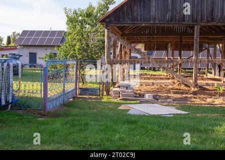 Das Skelett einer alten, zerstörten Scheune, die an einem sonnigen Tag abgerissen wird. Gras Stockfoto