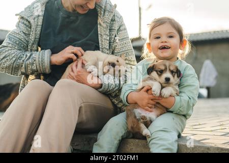 Glück, Liebe und Tierheim kümmern sich um eine Mutter, Kind umarmt und hält Welpen zusammen mit einem Lächeln im Hinterhof. Haustiere. Glücklich Stockfoto