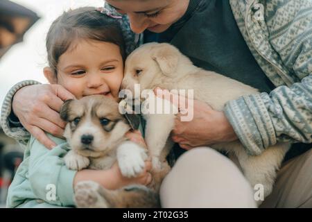 Porträt eines glücklichen Mädchens und ihrer Mutter, die Welpen halten. Haustiere. Einen schönen Familientag. Stockfoto