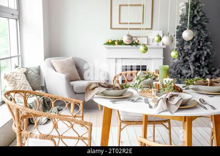 Weihnachtstisch mit hängenden Kugeln, brennenden Kerzen und Tannenzapfen im Wohnzimmer Stockfoto