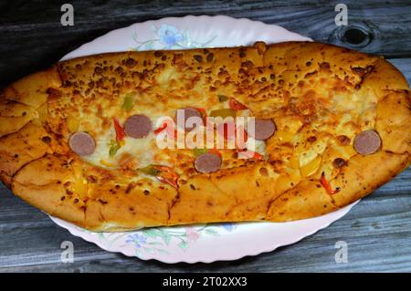 Käse-Fougasse-Brot mit grünen Paprikasscheiben, Käse und geschnittener Wurst, die im Ofen gebacken werden, ist eine typische Brotsorte Stockfoto