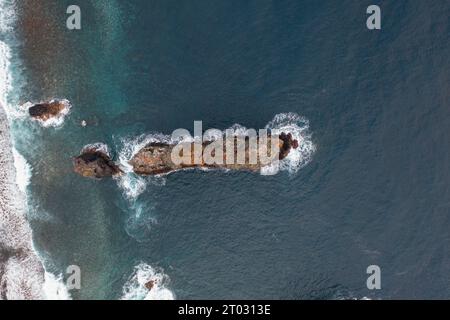 Großartiges Drohnenfoto von einer Klippe auf Madeira, wo ein Leuchtturm an der Spitze der Klippe steht und Schiffe vor der Landung warnt. Stockfoto