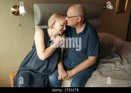 Glückliches älteres Paar. Eine ältere Frau streichelt die Hand ihres Mannes und drückt sanft gegen ihn. Stockfoto