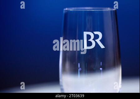 Das Logo des Bayerischen Rundfunks BR auf einem Glas vor dem TV-Duell der Sendung BR24 Wahl - die Konfrontation zur Landtagswahl 2023 im BR-Studio in Nürnberg. Der Bayerische Rundfunk ist die Landesrundfunkanstalt im Freistaat Bayern mit Sitz in München. Er ist Mitglied der Arbeitsgemeinschaft der öffentlich-rechtlichen Rundfunkanstalten der Bundesrepublik Deutschland ARD und hat die Rechtsform einer Anstalt des öffentlichen Rechts. Themenbild, Symbolbild Nürnberg, 03.10.2023 Bayern Deutschland *** das Logo des Bayerischen Rundfunks BR auf einem Glas vor dem TV-Duell der Sendung BR24 Elect Stockfoto