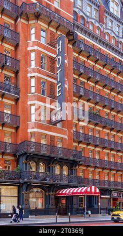 Das Hotel Chelsea dominiert den Block mit seiner dunkelroten Fassade, markanten Balkonen aus Eisen und einem dreistöckigen beleuchteten Schild an der 222 W 23rd Street in Midtown. Stockfoto