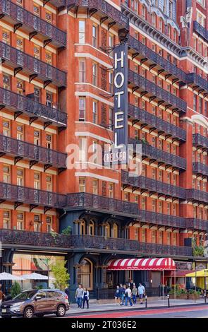 Das Hotel Chelsea dominiert den Block mit seiner dunkelroten Fassade, markanten Balkonen aus Eisen und einem dreistöckigen beleuchteten Schild an der 222 W 23rd Street in Midtown. Stockfoto