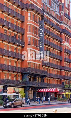 Das Hotel Chelsea dominiert den Block mit seiner dunkelroten Fassade, markanten Balkonen aus Eisen und einem dreistöckigen beleuchteten Schild an der 222 W 23rd Street in Midtown. Stockfoto