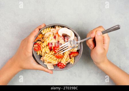 Essen Sie einen Nudelsalat mit Pilzscheiben, Tomaten, roten Pfefferstückchen und Thunfisch, gesunde Lebensmittel mit Gemüse, frische Bio-Ernährung Stockfoto