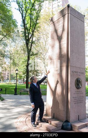 New York, Usa. Oktober 2023. Philip H. Dybvig, der 2022 den Nobelpreis für Wirtschaft gewann, zeigt seinen Finger auf seinen Namen, der allein mit anderen fünf Amerikanern eingeschrieben war, die den Preis 2022 am Nobel Monument im Theodore Roosevelt Park in New York gewannen. Der Obelisk ehrt alle amerikanischen Nobelpreisträger sowie den Gründer des Nobelpreises, den schwedischen Erfinder Alfred Nobel. Schüler der 7. Klasse der Andersen-Schule 334 nahmen Teil. (Foto: Lev Radin/Pacific Press) Credit: Pacific Press Media Production Corp./Alamy Live News Stockfoto