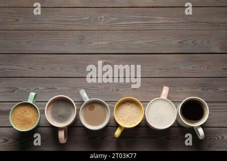 Viele verschiedene Tassen mit aromatischem Kaffee auf Holztisch, flach liegend. Leerzeichen für Text Stockfoto