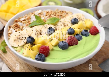 Leckere Matcha Smoothie Schüssel serviert mit frischem Obst und Haferbrei auf dem Tisch, Nahaufnahme. Gesundes Frühstück Stockfoto