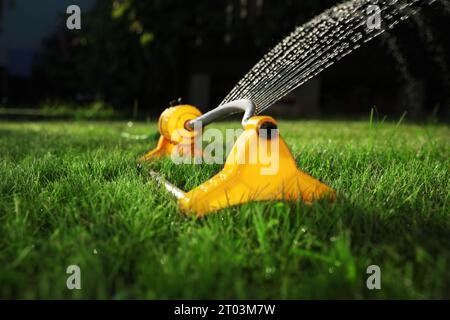 Automatischer Sprinklerschutz zur Bewässerung von grünem Gras auf dem Rasen im Garten, Nahaufnahme. Bewässerungssystem Stockfoto