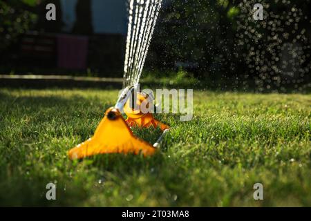 Automatischer Sprinklerschutz zur Bewässerung von grünem Gras an sonnigen Tagen im Freien. Bewässerungssystem Stockfoto