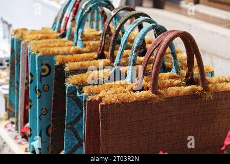 Eine Reihe von schrulligen, einzigartigen, seidenstickenden, mehrfarbigen Taschen, Taschen oder Handtaschen, mit gebogenen steifen Griffen, goldenen Tufts und verschiedenen Designmustern. Stockfoto