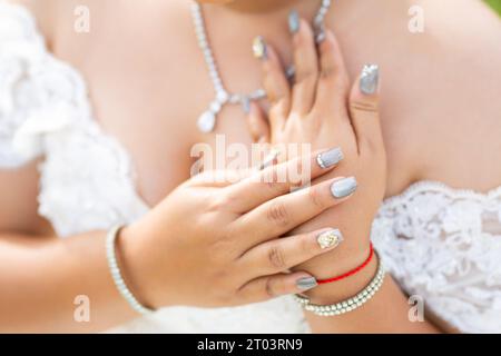 Hol dir eine Braut Maniküre mit silbernem und weißem nagellack. Blumen und Glitzer Nahaufnahme der Hände der Braut auf einem Strauß weißer Rosen Stockfoto