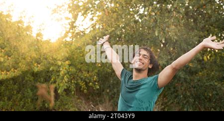 Glücklicher junger arabischer Mann, der die Freiheit unter Regentropfen genießt und die Kühle des Sommers bei Sonnenuntergang genießt. Kopierbereich Stockfoto