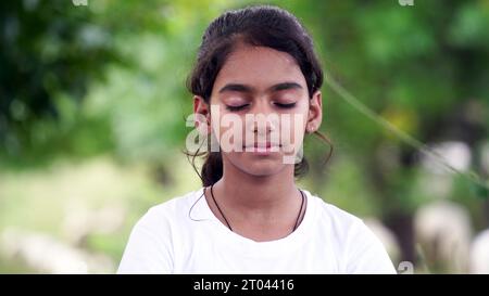 Charmantes kleines Mädchen, das ernsthafte Yoga-Meditation im Garten macht. Kleines indisches Mädchen, das Meditation macht Stockfoto