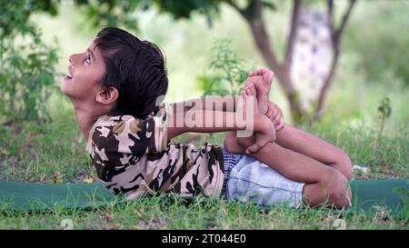 Porträt eines wunderschönen Kindes, das im Freien Yoga übt. Schöne Kinder üben Yoga Asana oder machen Gymnastik Übungen. Kleine Kinder, die in Lotus po meditieren Stockfoto