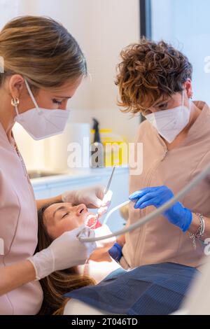 Ein Techniker, der den Mund einer Frau untersucht, die in einer Zahnklinik auf einem Stuhl liegt Stockfoto