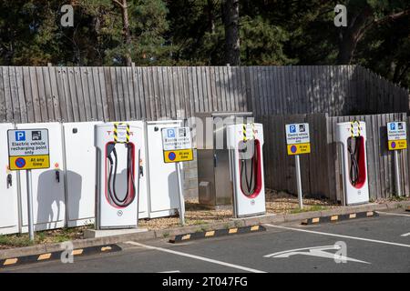 Tesla-Ladegeräte für Elektrofahrzeuge bei Fleet Autobahndiensten in Hampshire, Schilder weisen darauf hin, dass die Ladegeräte nicht für den Einsatz in England, Großbritannien verfügbar sind Stockfoto