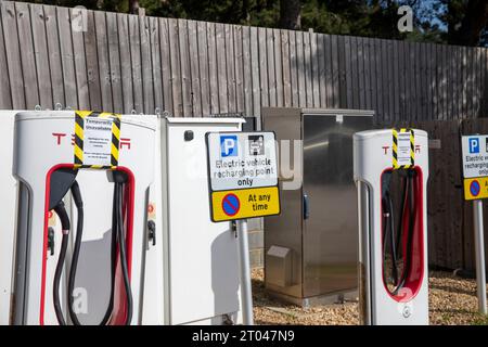 Tesla-Ladegeräte für Elektrofahrzeuge bei Fleet Autobahndiensten in Hampshire, Schilder weisen darauf hin, dass die Ladegeräte nicht für den Einsatz in England, Großbritannien verfügbar sind Stockfoto