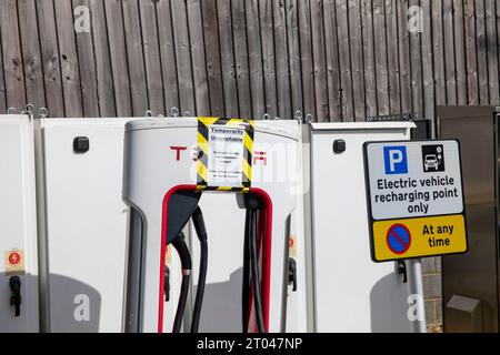 Tesla-Ladegeräte für Elektrofahrzeuge bei Fleet Autobahndiensten in Hampshire, Schilder weisen darauf hin, dass die Ladegeräte nicht für den Einsatz in England, Großbritannien verfügbar sind Stockfoto