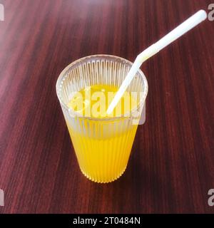 Ein Glas Orangeneis wird auf einem braunen Tisch serviert Stockfoto