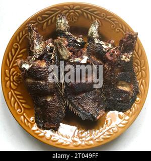 Einige Süßwasserfische namens Papuyu oder Betik, die wissenschaftlich Anabas testudineus genannt werden, werden auf einer braunen Platte gebraten Stockfoto